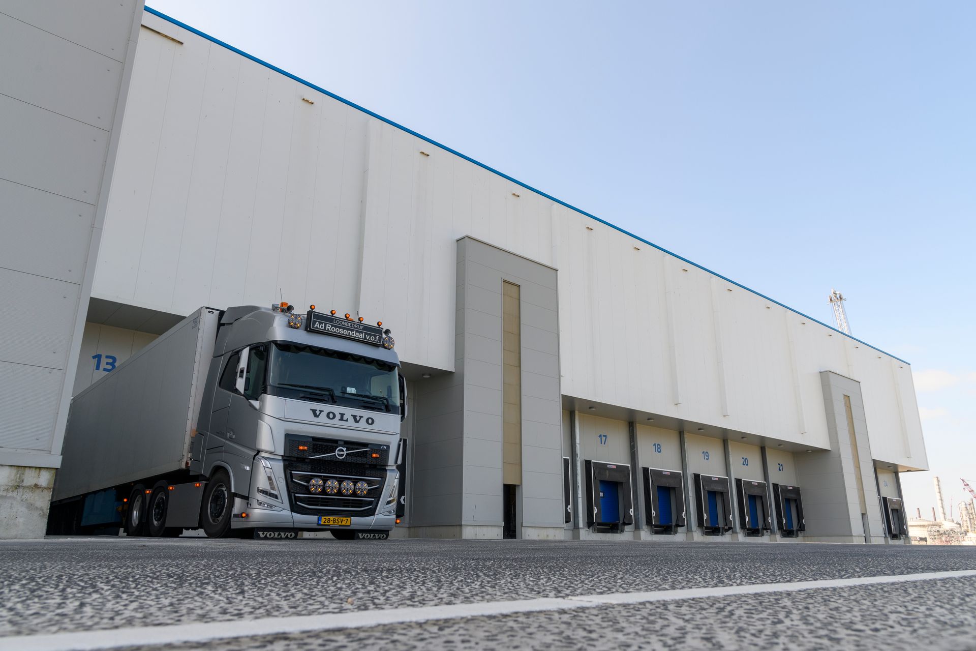 Een vrachtwagen staat geparkeerd voor een groot wit gebouw.