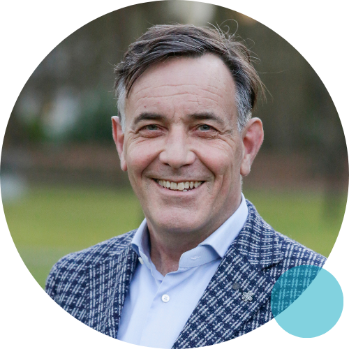 Een man in pak staat lachend in een kring.