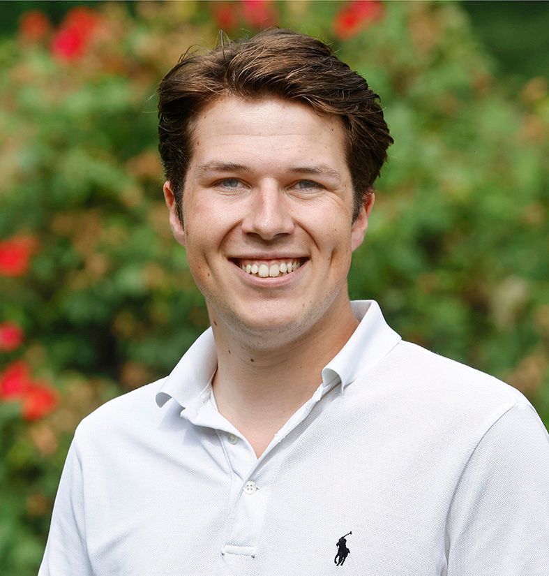 Een man in een wit poloshirt lacht naar de camera