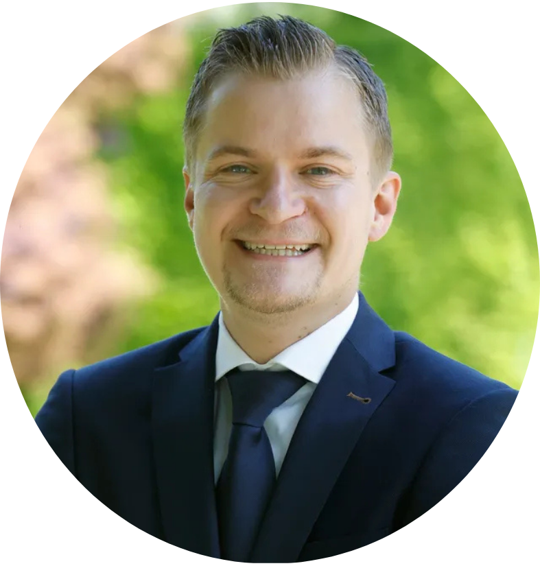 Een man in een wit overhemd lacht, met zijn armen over elkaar.