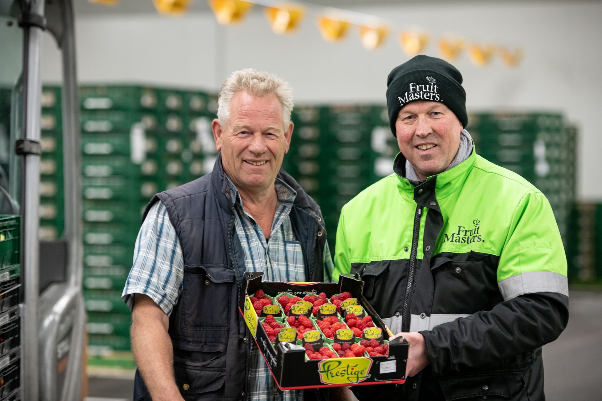 Twee mannen staan ​​naast elkaar met een doos aardbeien in hun handen.