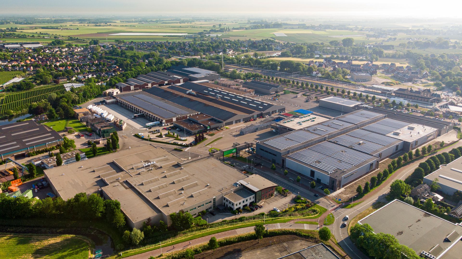 Een luchtfoto van een groot industriegebied met veel gebouwen en zonnepanelen op de daken.