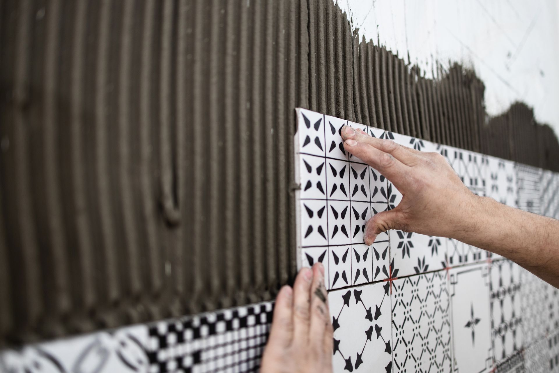Una persona sta applicando l'adesivo per piastrelle su un muro.