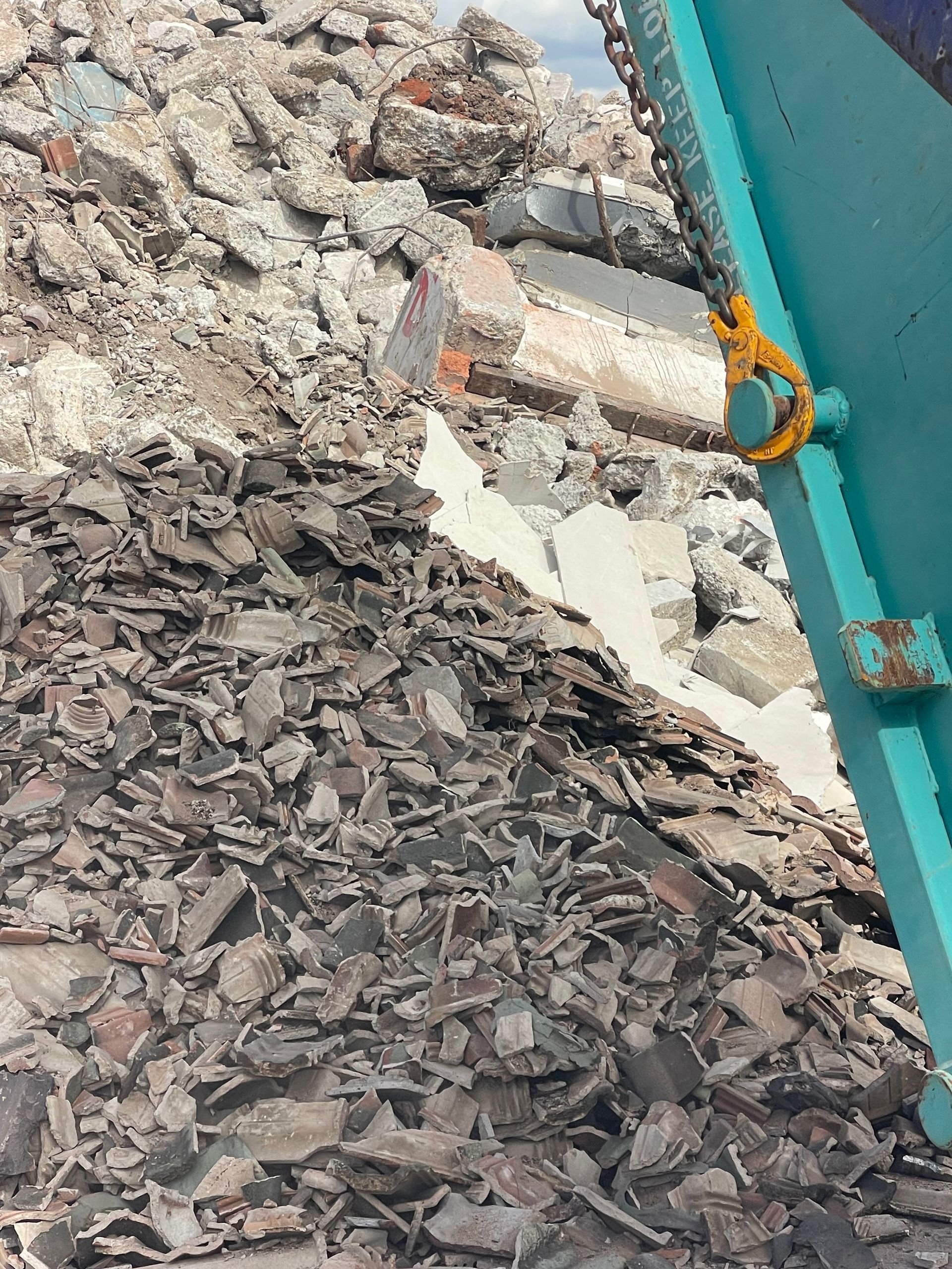 Debris Pile With a Turquoise Crane Component; Gray and Brown Rubble — Mackay Skip Hire In Andergrove, QLD