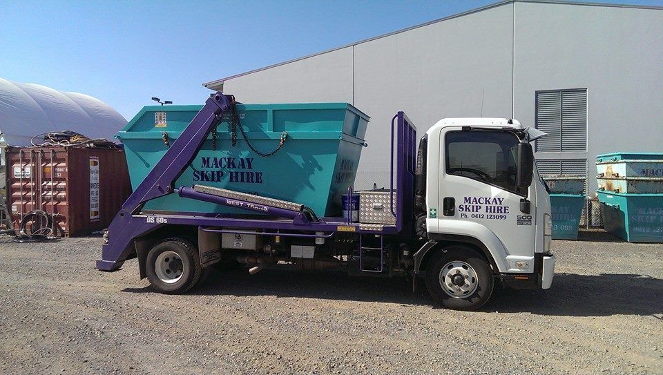 Green Skip Bin on a Road With Orange Cones. Houses and Trees — Mackay Skip Hire In Andergrove, QLD