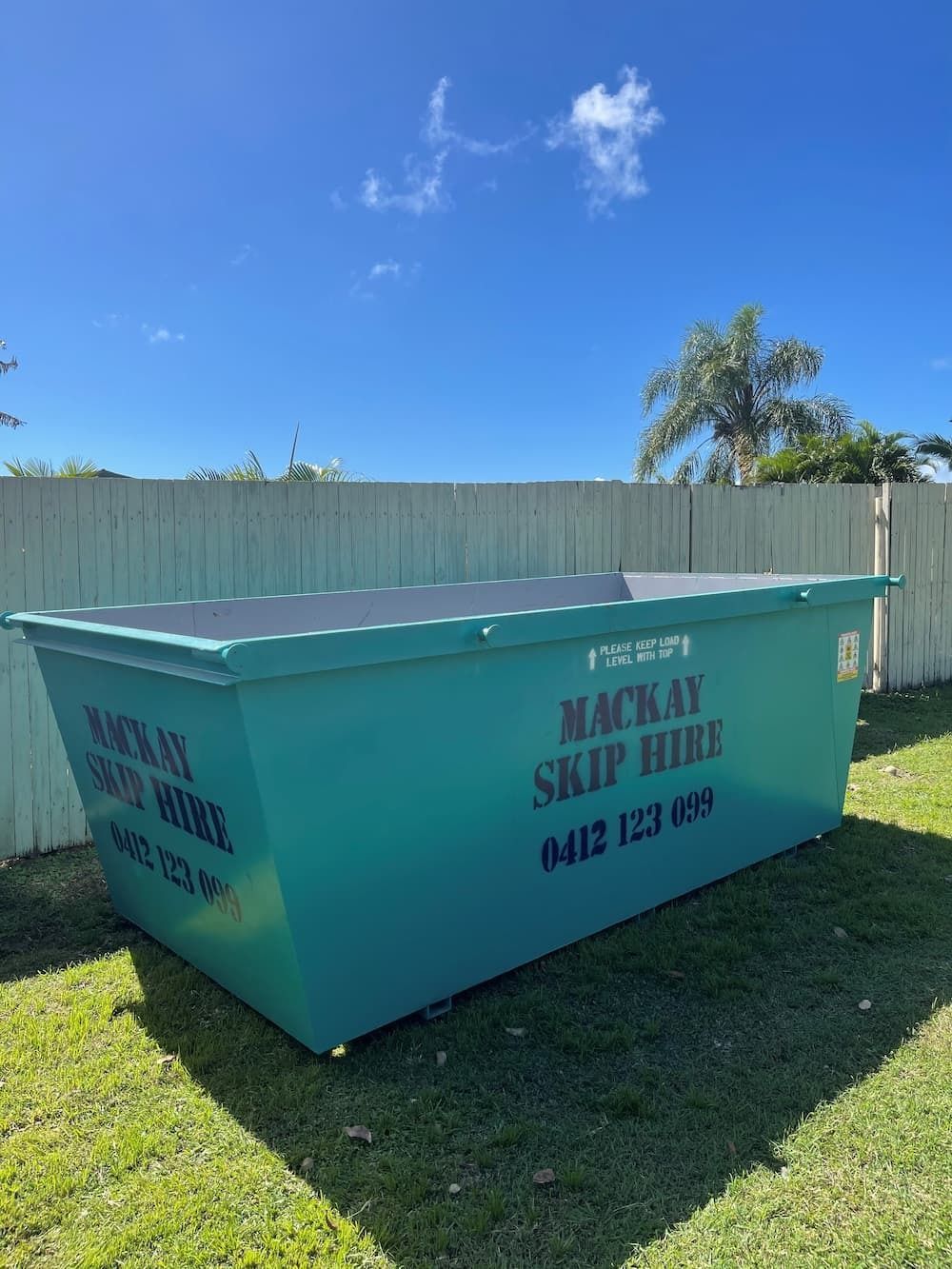 Turquoise Skip Bin on Grass, Text Reads Mackay Skip Hire — Mackay Skip Hire In Andergrove, QLD
