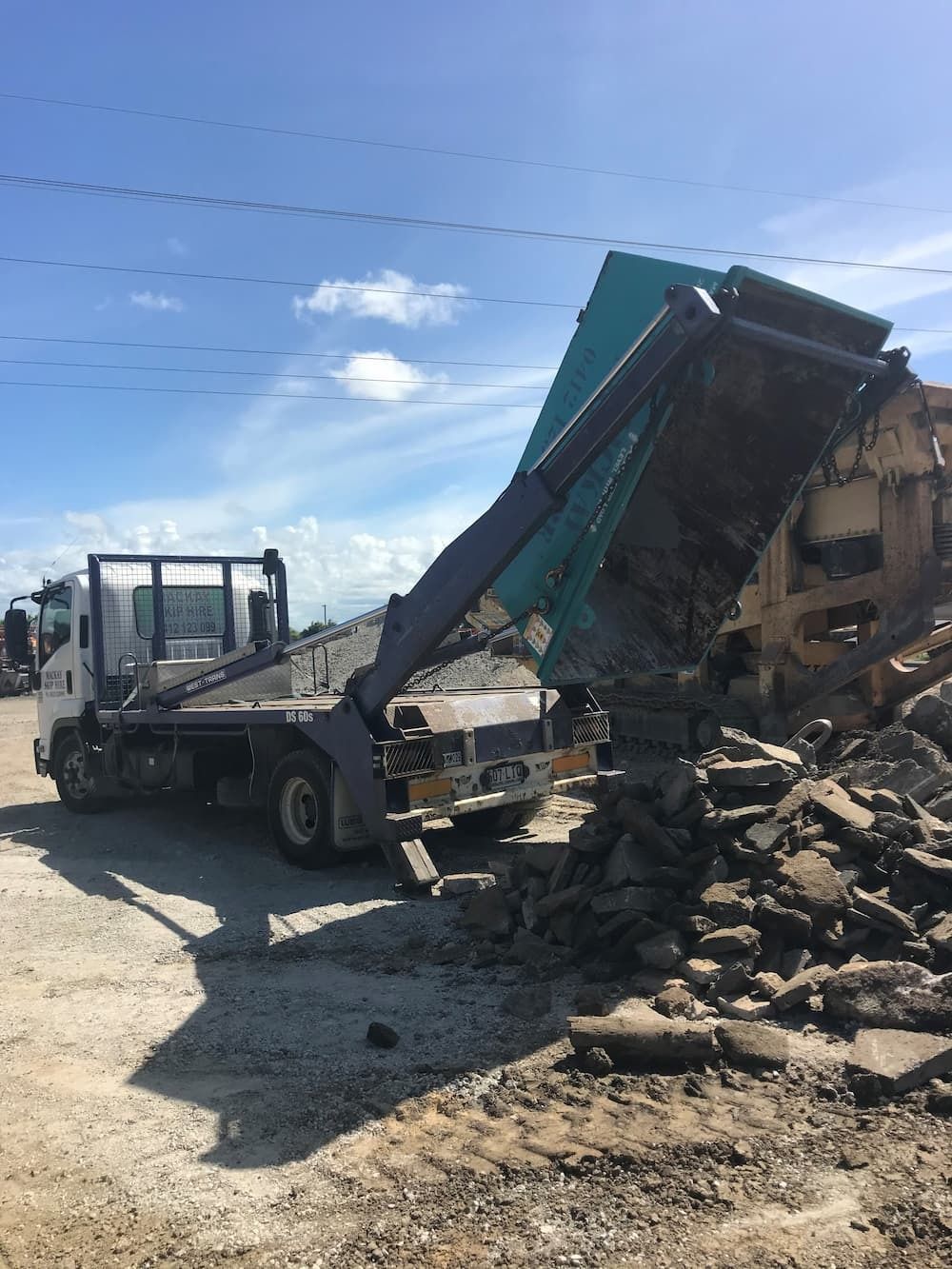 A Truck With Its Bed Raised, Dumping Rubble From a Demolition Site — Mackay Skip Hire In Andergrove, QLD