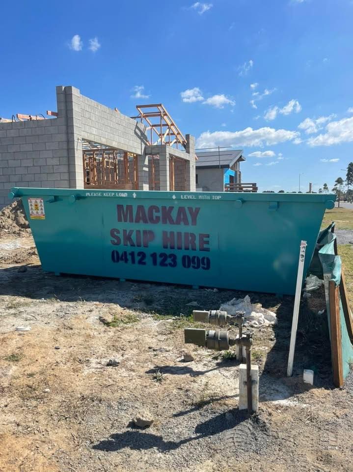 Green Skip Bin Labeled Mackay Skip Hire on Construction Site — Mackay Skip Hire In Andergrove, QLD