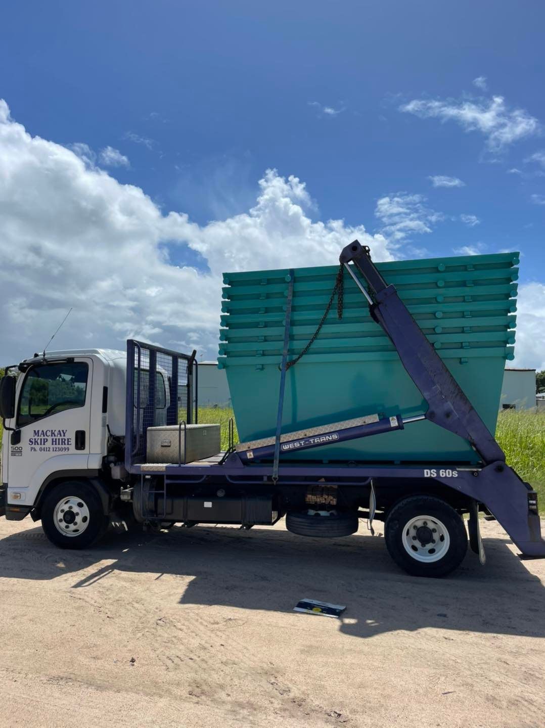 White Truck With a Teal Dumpster on the Back, Under a Blue Sky — Mackay Skip Hire In Andergrove, QLD