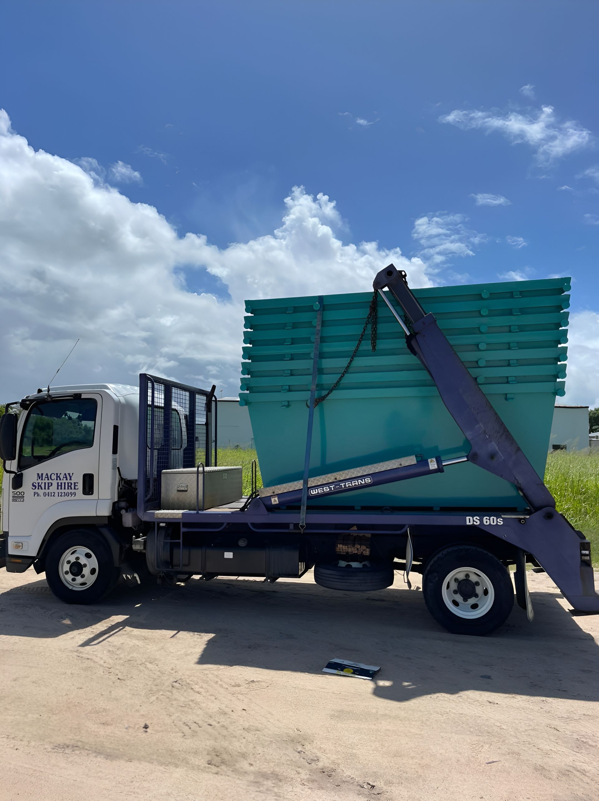 Red and Yellow Skip Bin Overflowing With Waste Next to a Building — Mackay Skip Hire In Andergrove, QLD