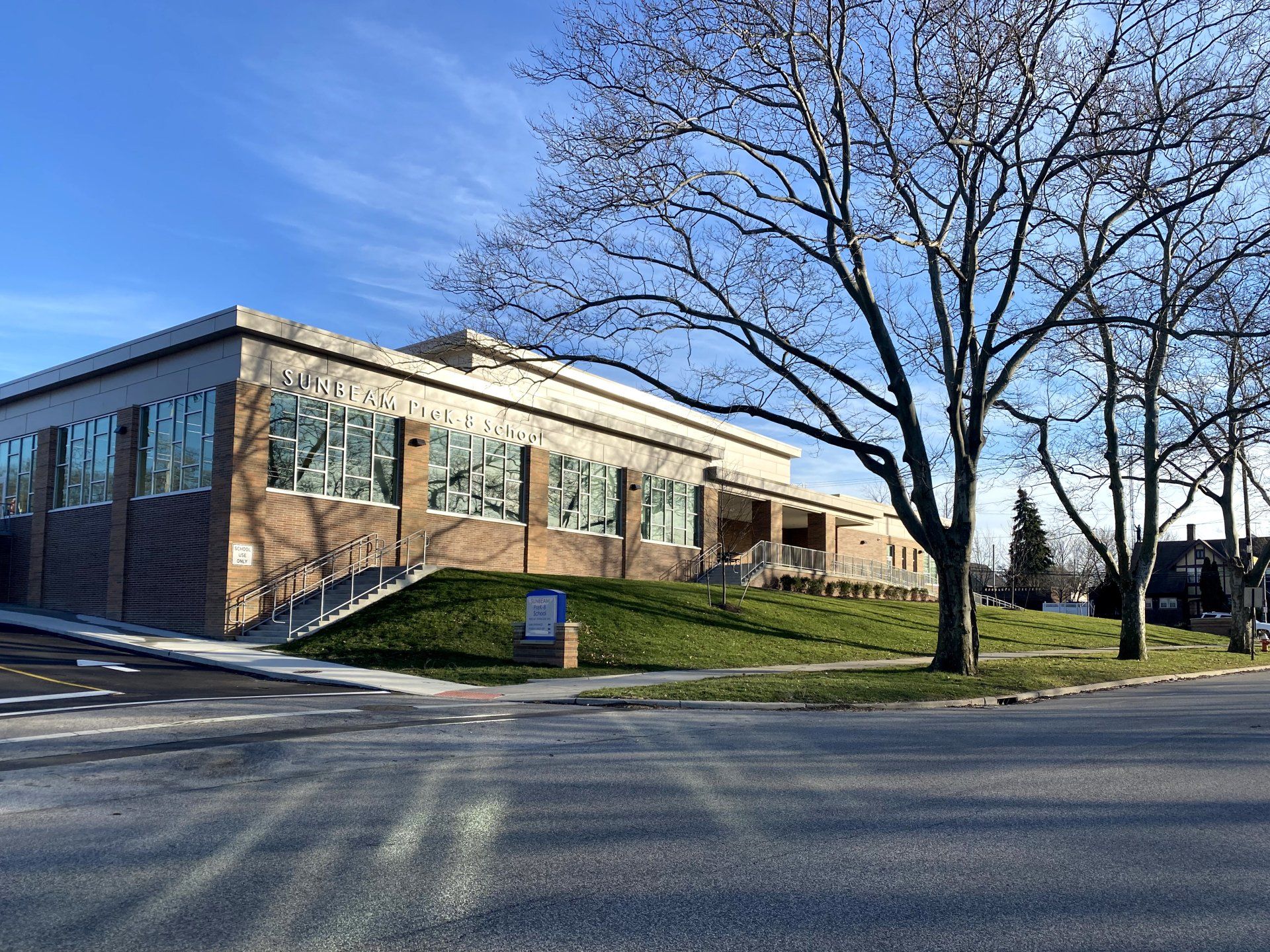 A large brick building with a lot of windows and trees in front of it.