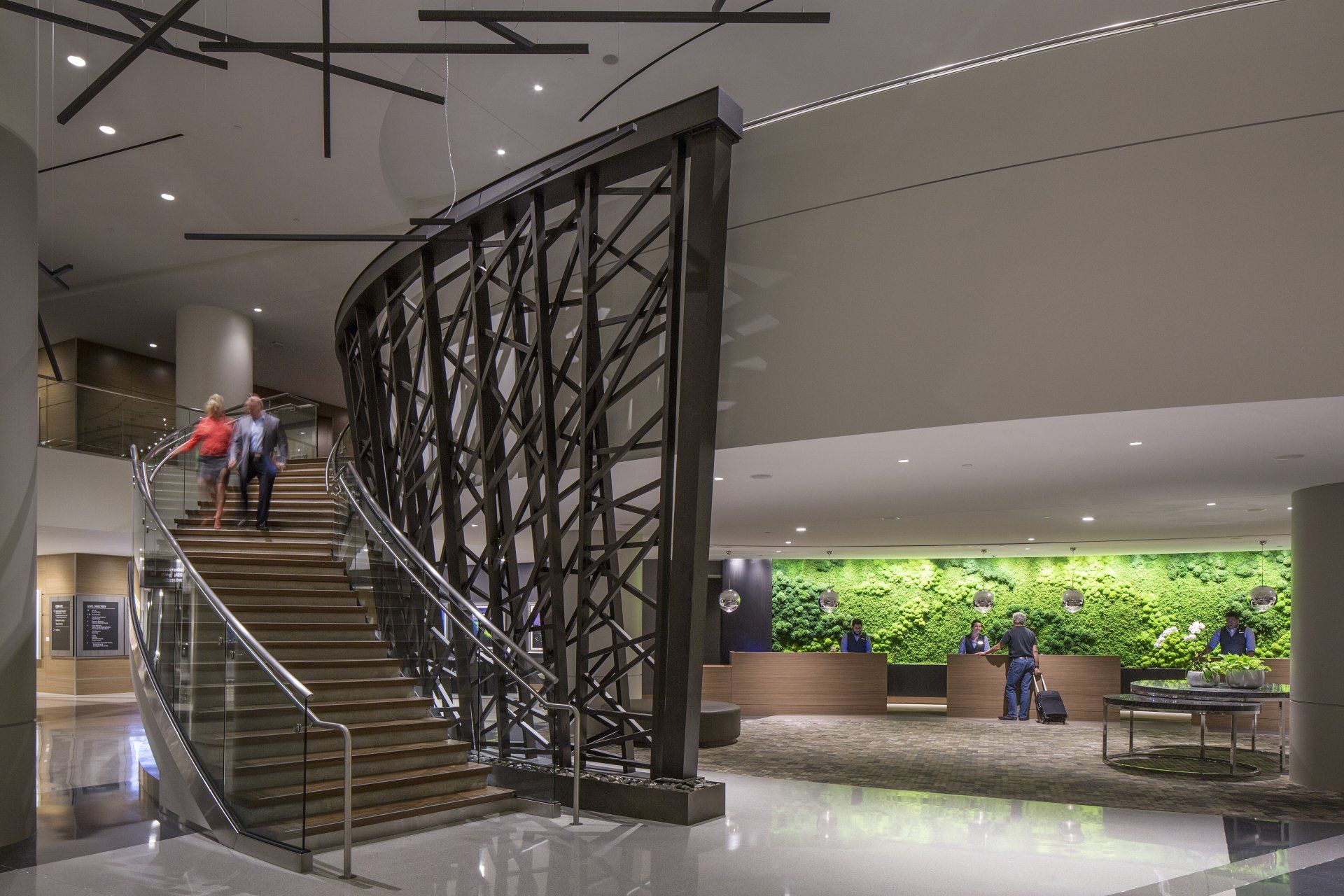 A lobby of a hotel with a staircase and a green wall.