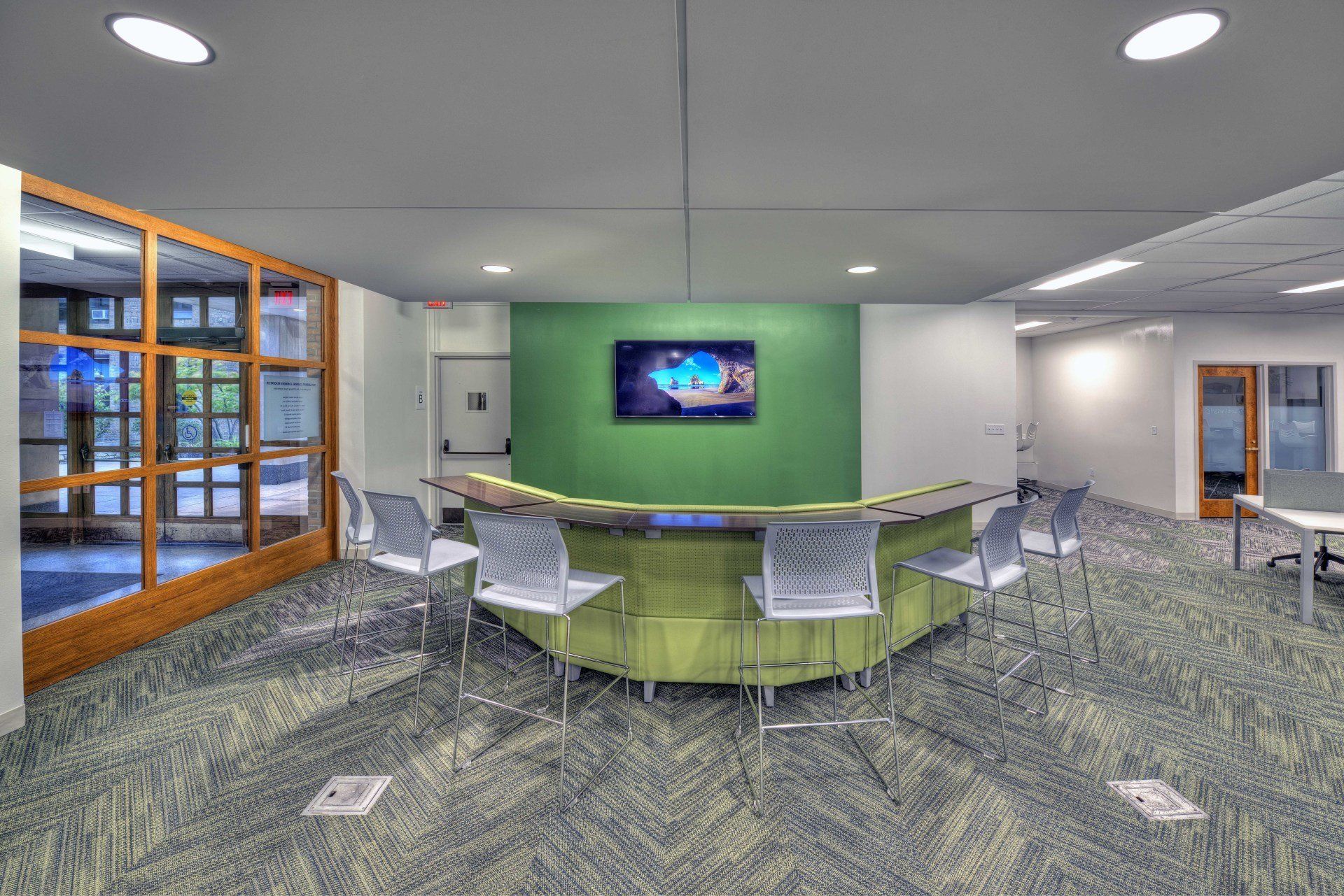 A room with a round table and chairs and a television on the wall.