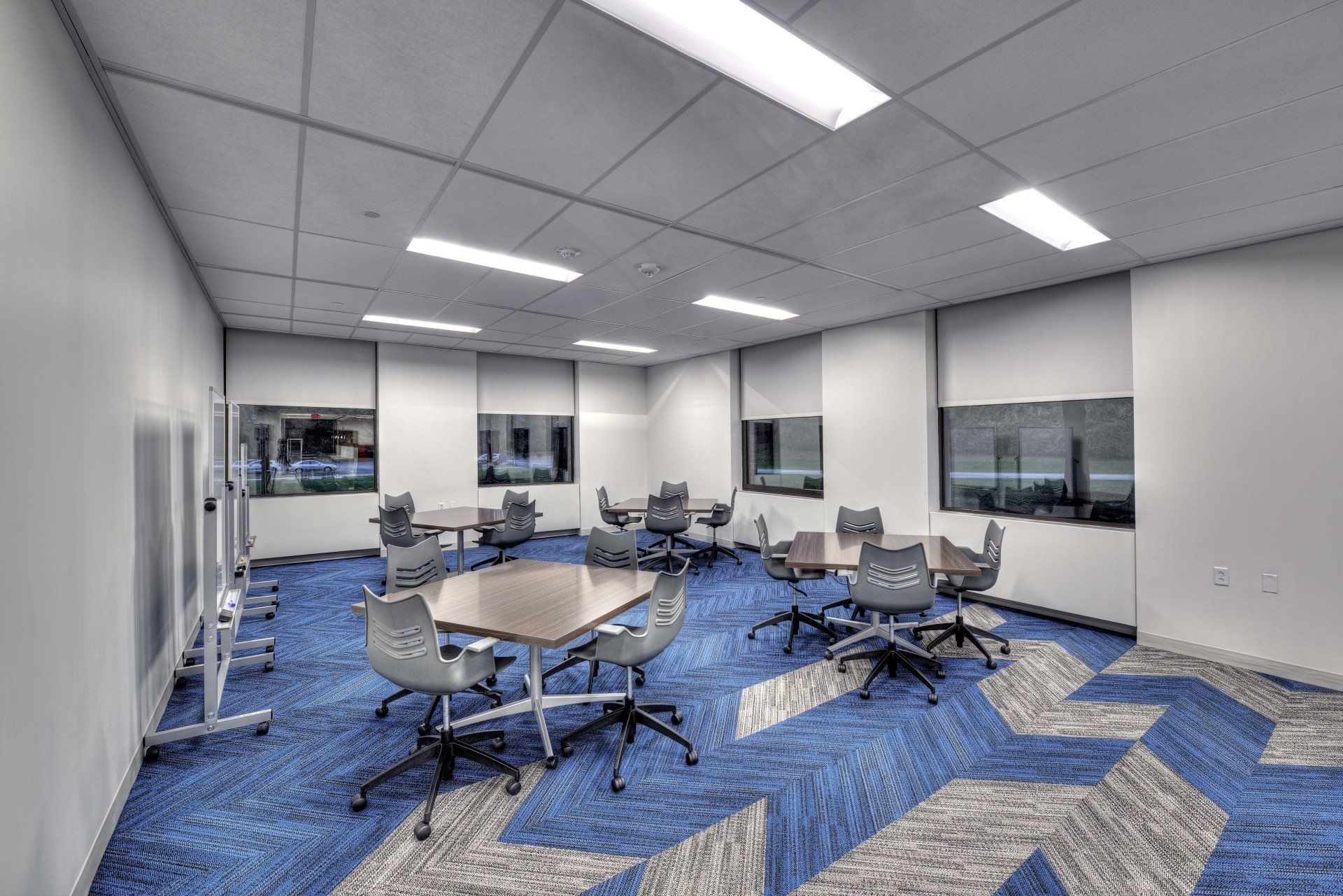 A large conference room with blue carpet and tables and chairs.
