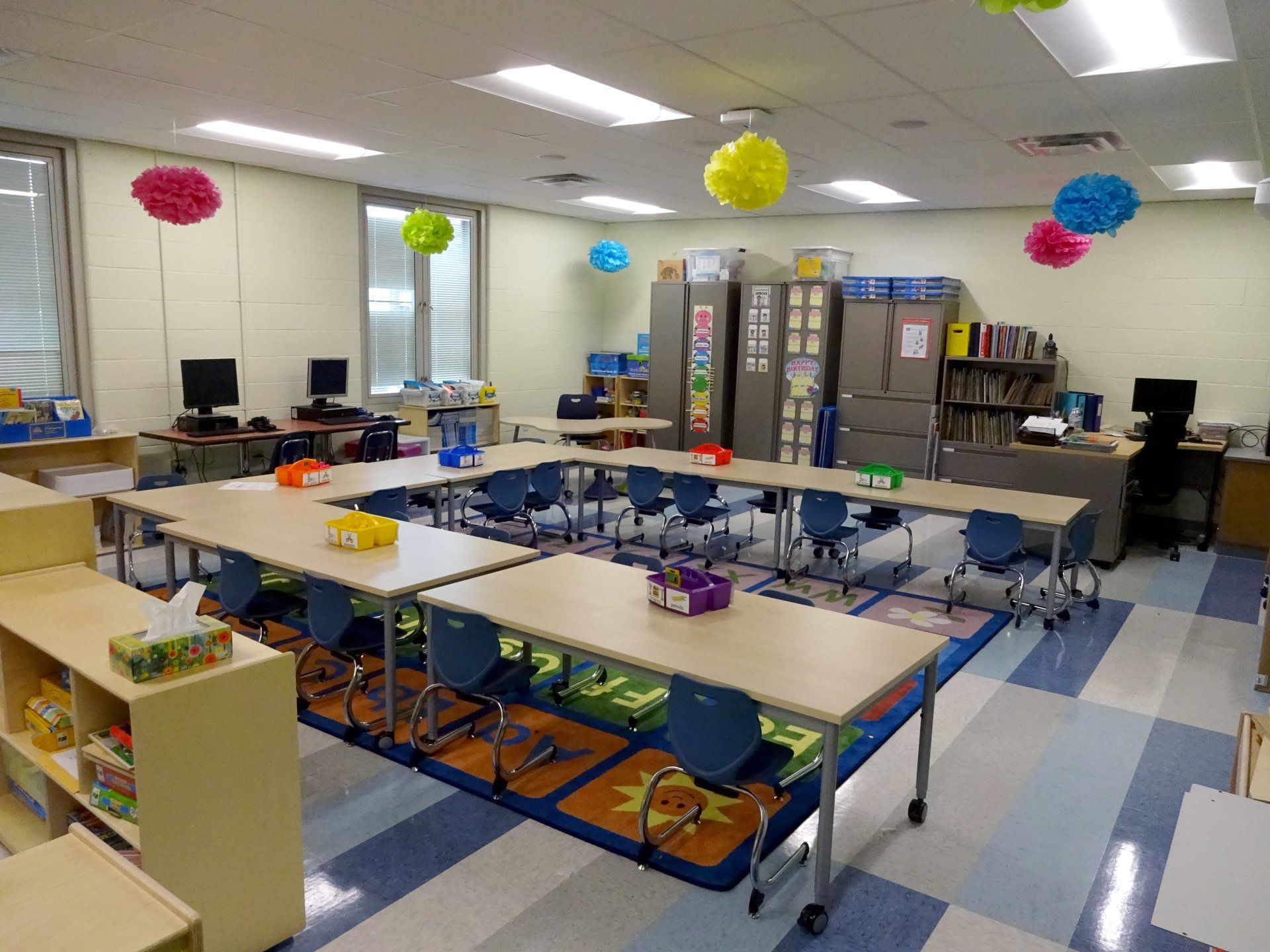 A classroom with tables and chairs and decorations on the ceiling