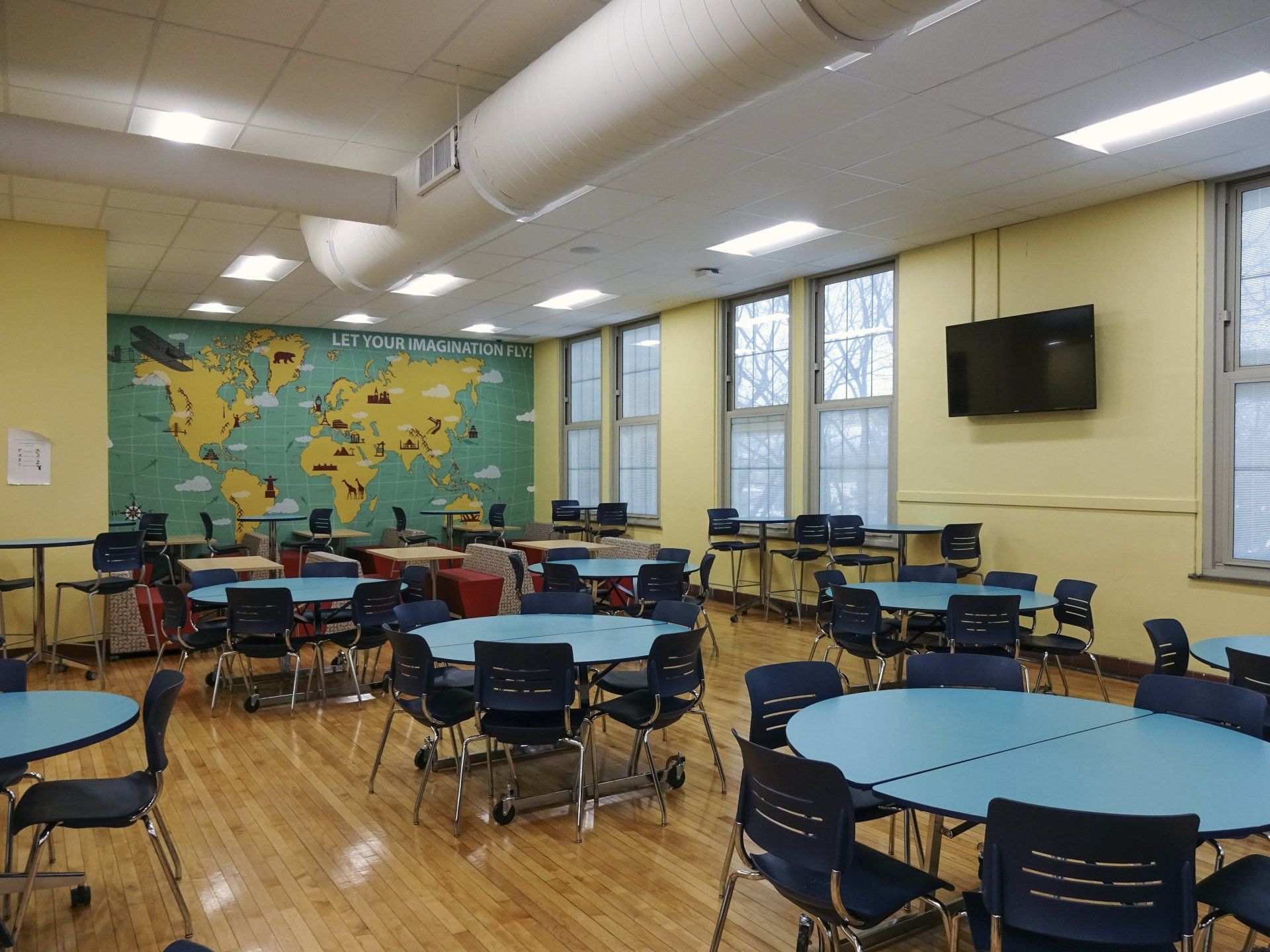 A large room with tables and chairs and a map of the world on the wall