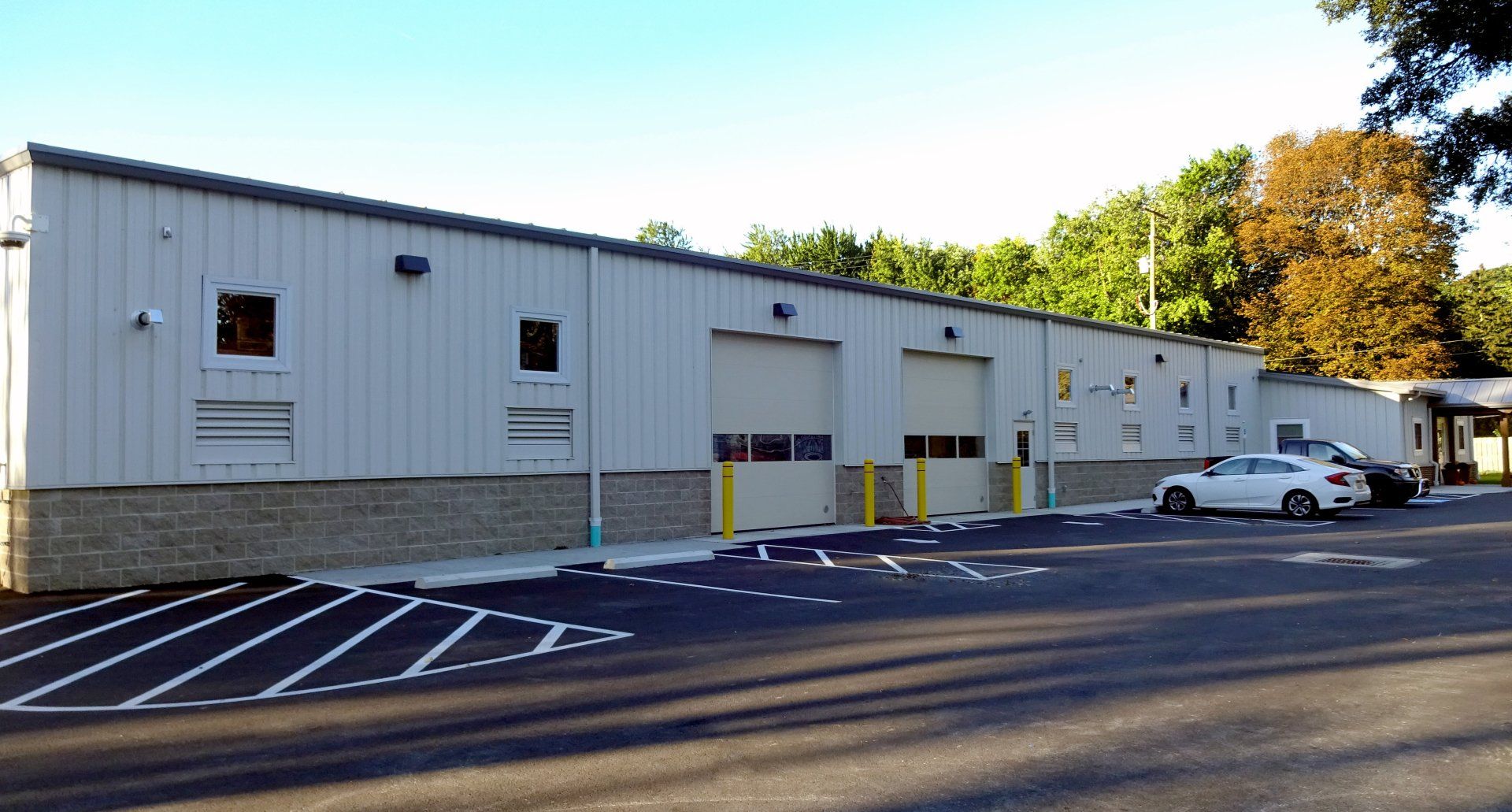 A white car is parked in front of a large building