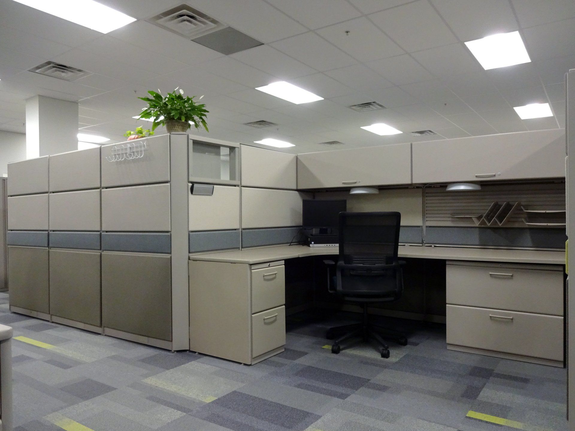 A cubicle in an office with a desk and chair.