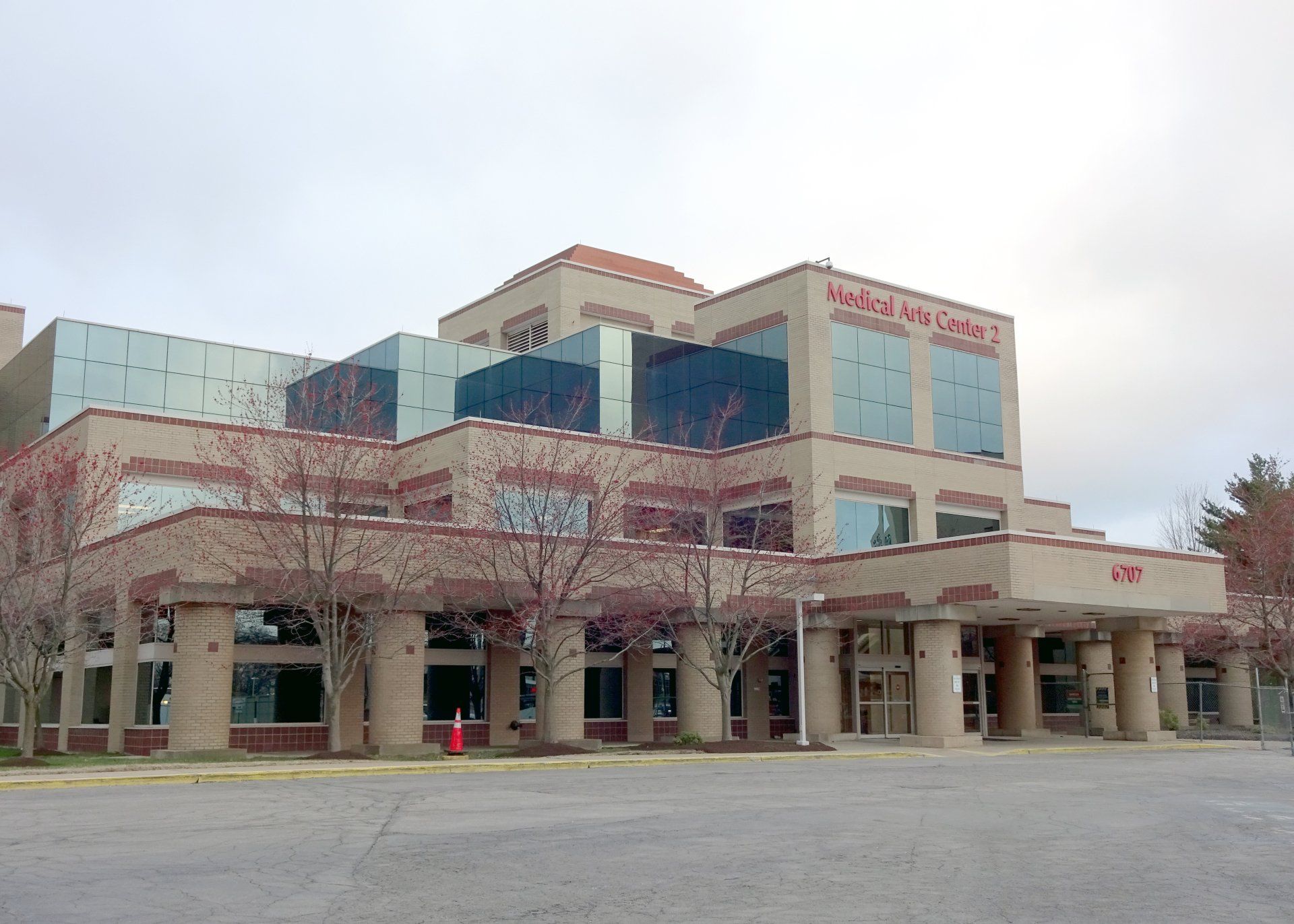 A large building with a lot of windows and a red cone in front of it.