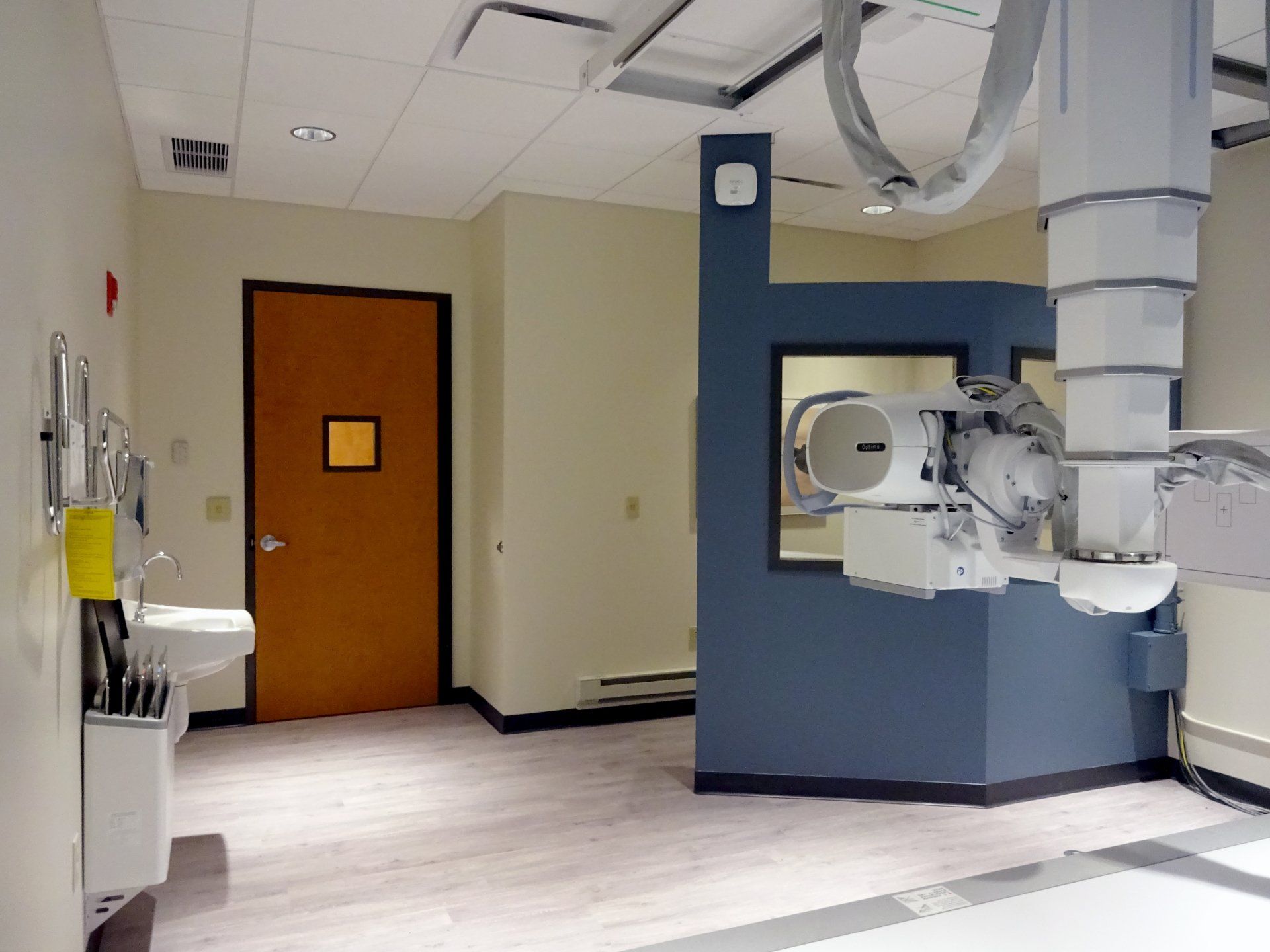 A hospital room with a x-ray machine hanging from the ceiling