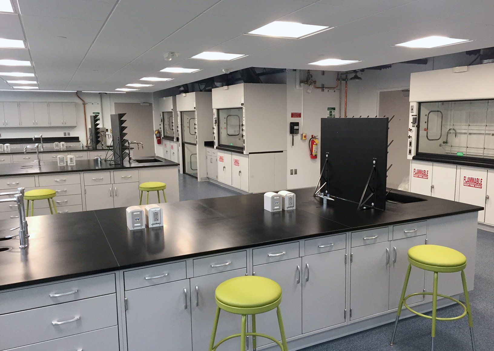 A laboratory with a long counter and green stools