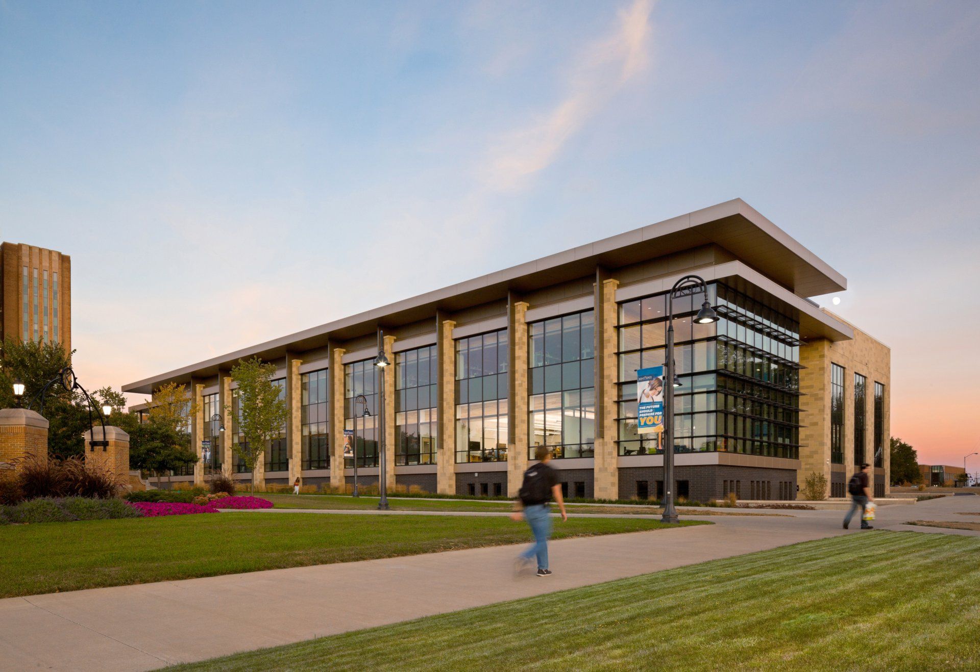 A man is walking in front of a large building with a lot of windows