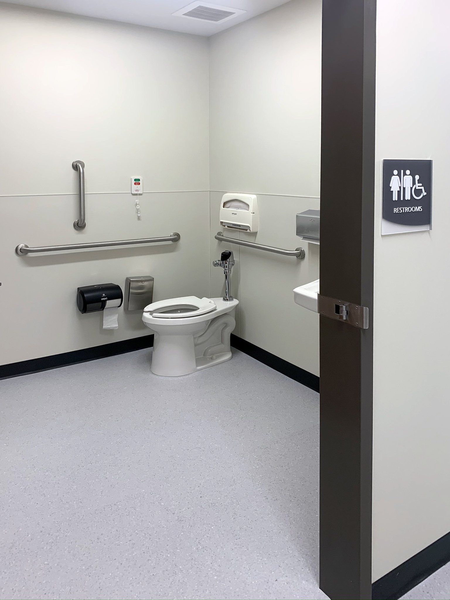 A handicapped bathroom with a toilet , sink and handrails.