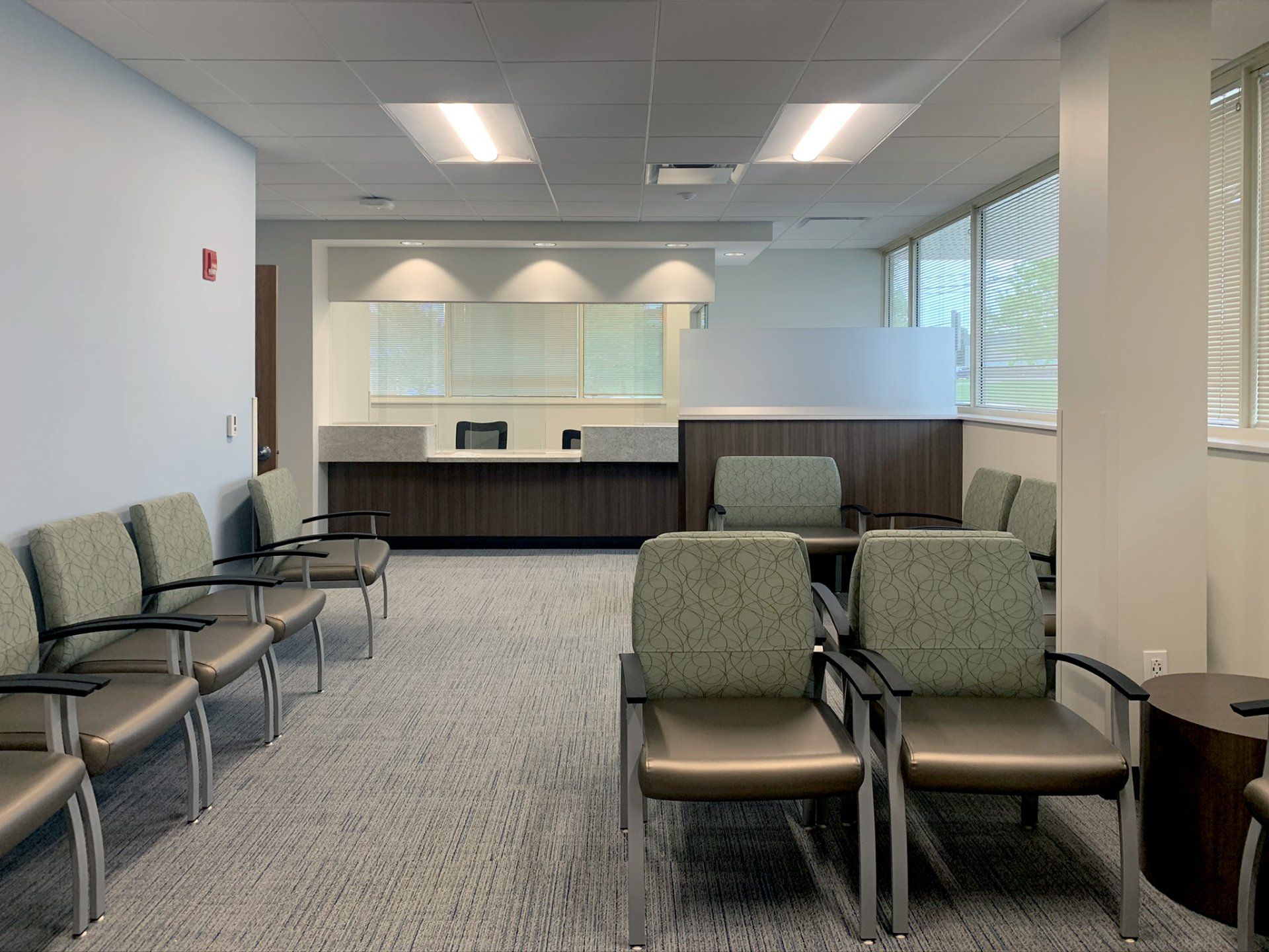 A waiting room with lots of chairs and a counter.