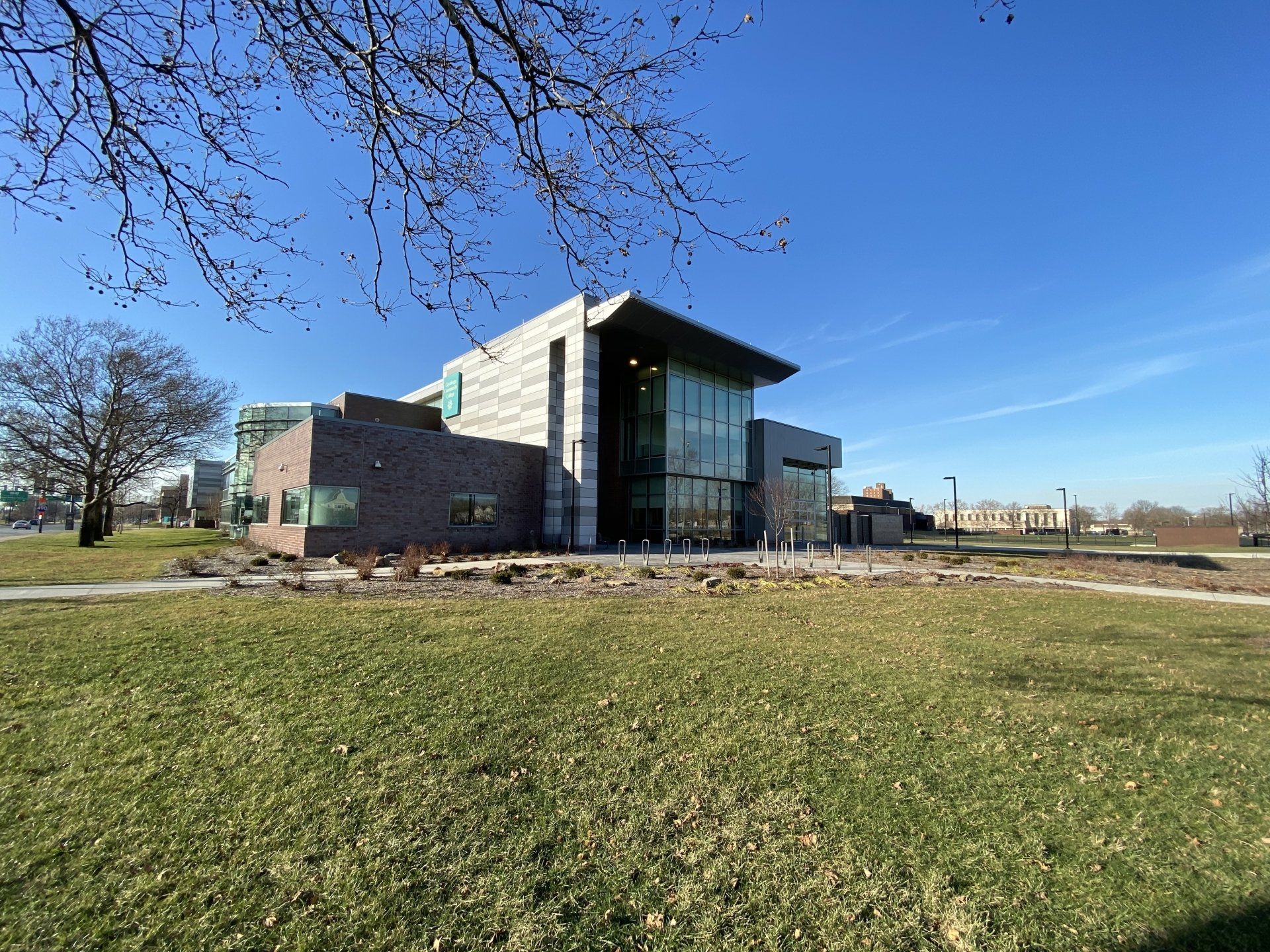 A large building with a lot of windows is sitting in the middle of a grassy field.