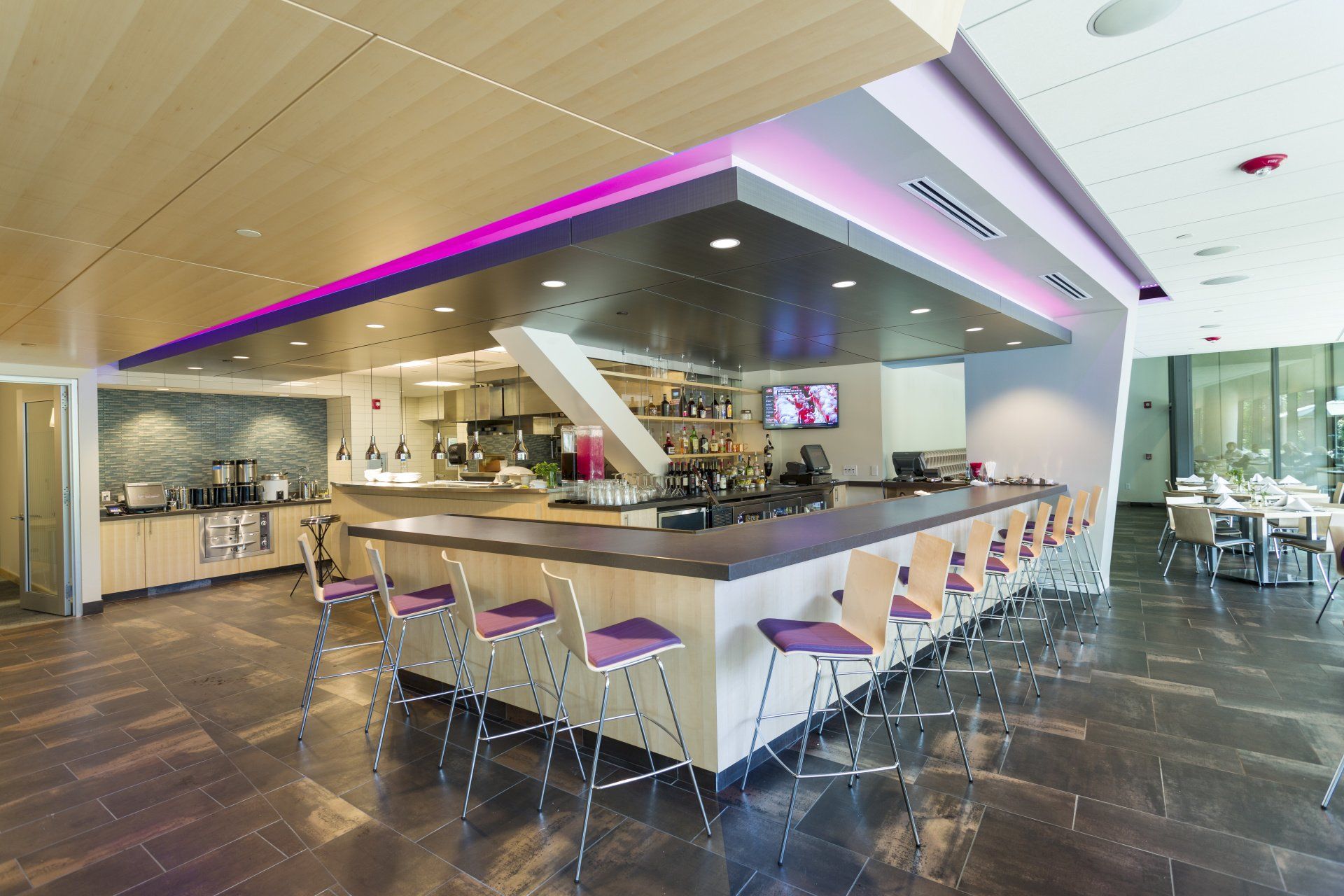 A restaurant with a long bar and purple lights on the ceiling