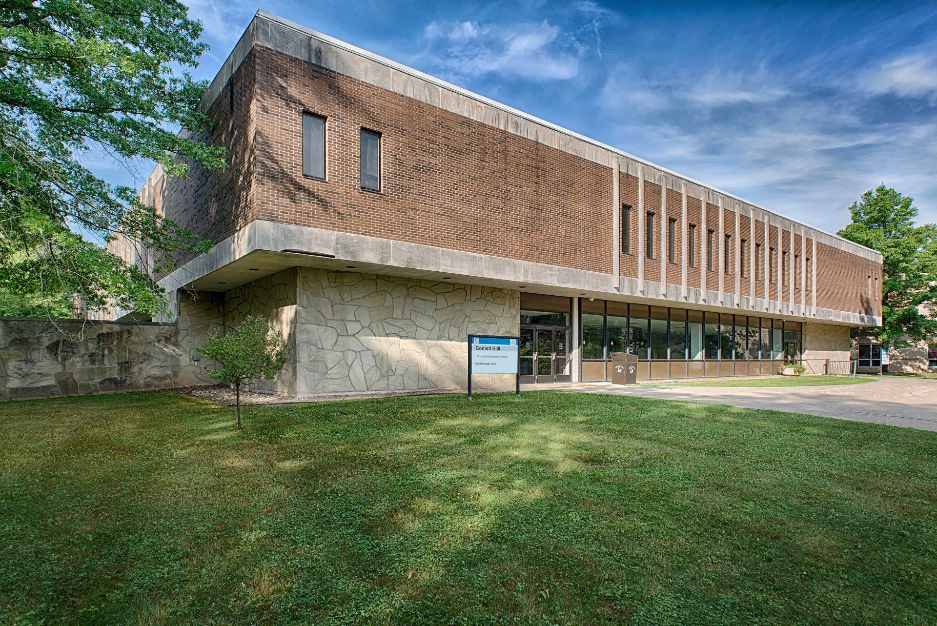 A large brick building with a lot of windows is sitting on top of a lush green field.