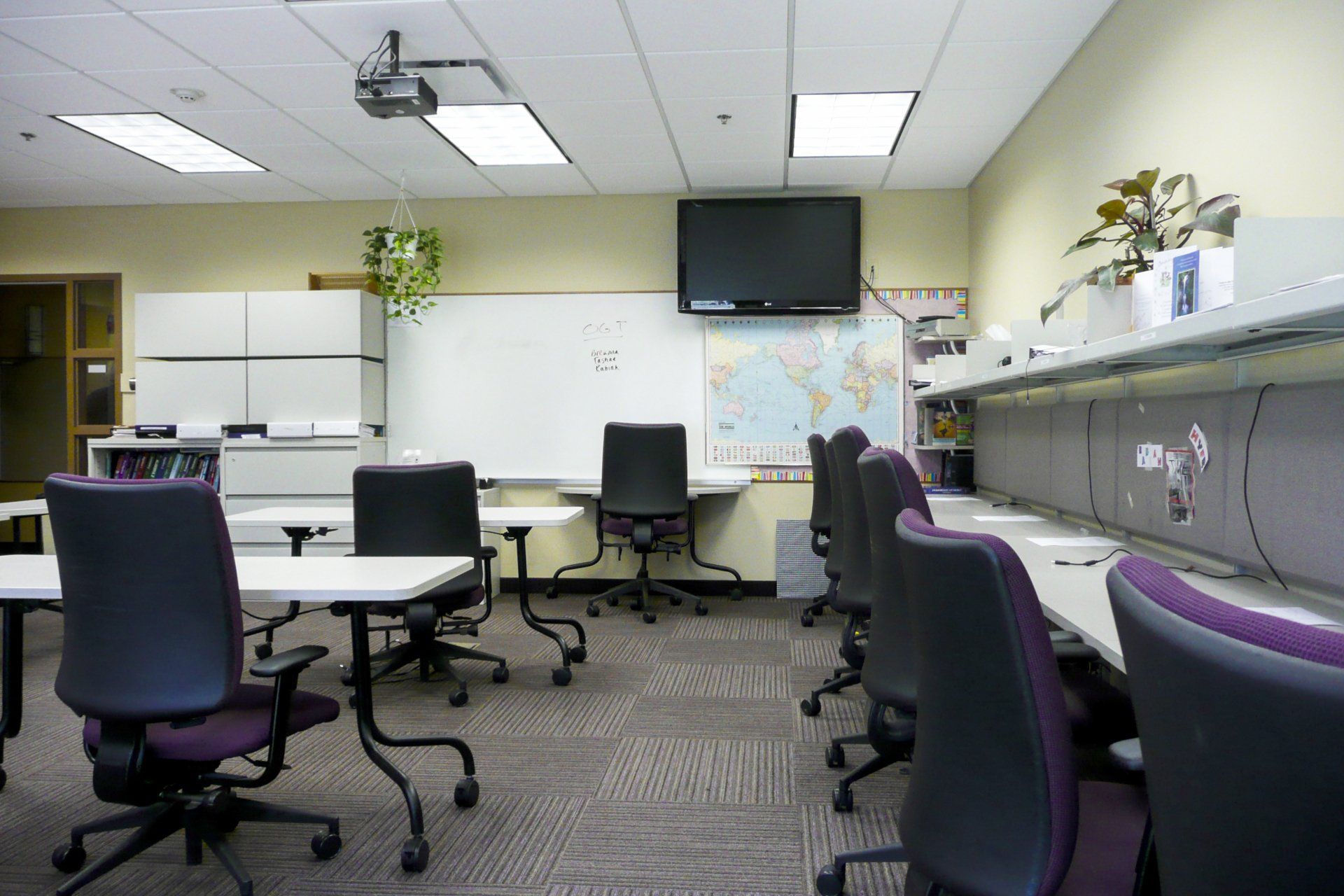 A classroom with tables and chairs and a map on the wall