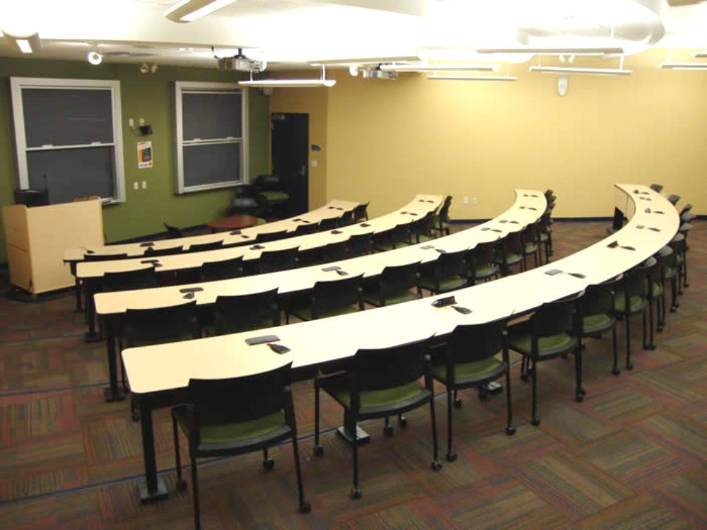 A classroom with a lot of tables and chairs