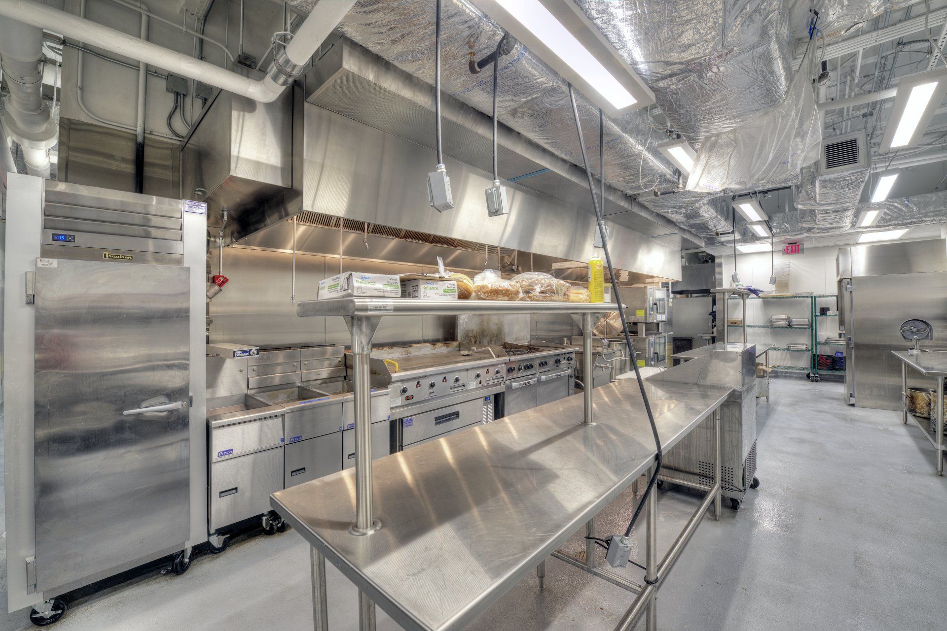 A kitchen with a lot of stainless steel appliances and tables