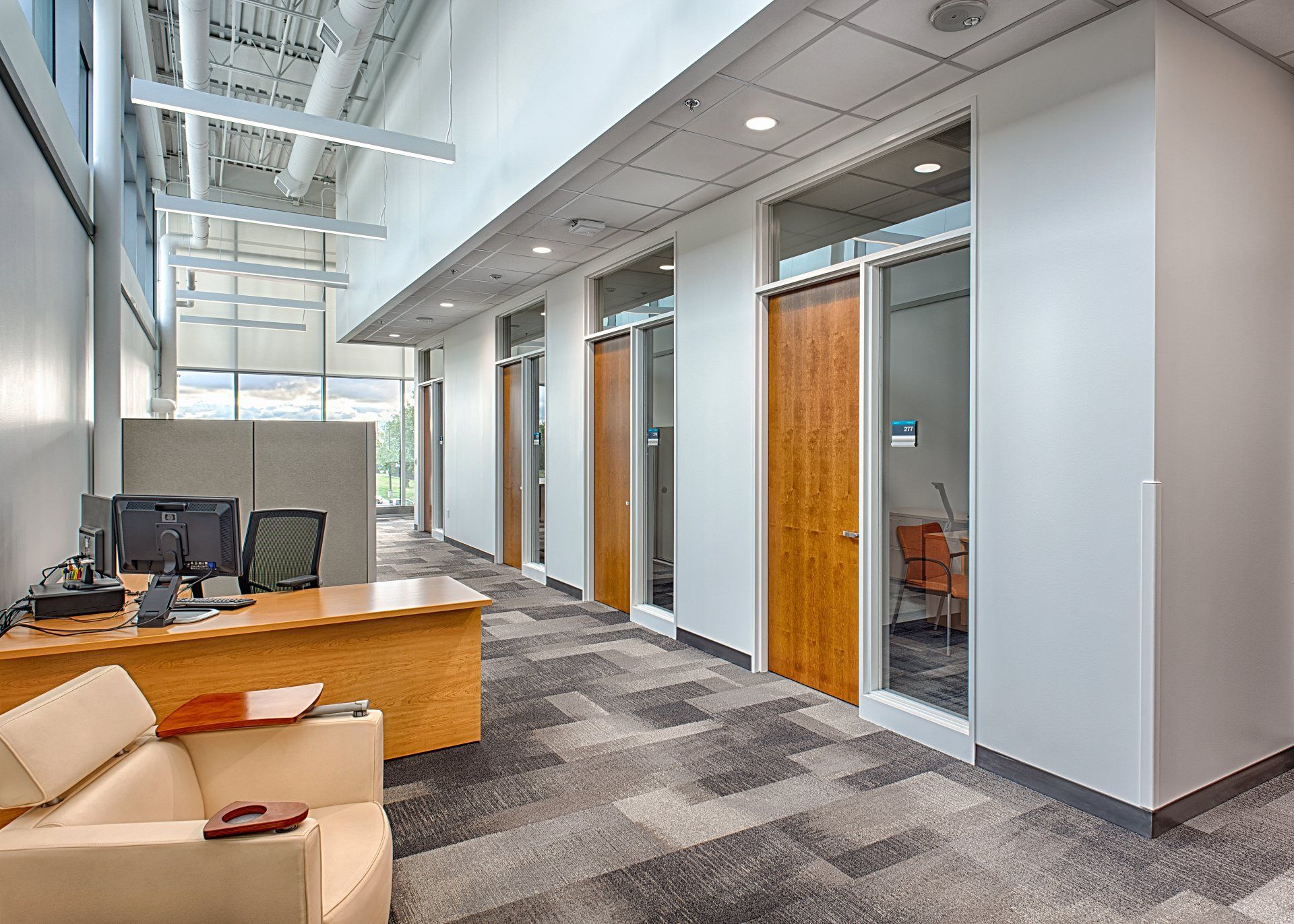 A long hallway in an office building with a desk and chairs.