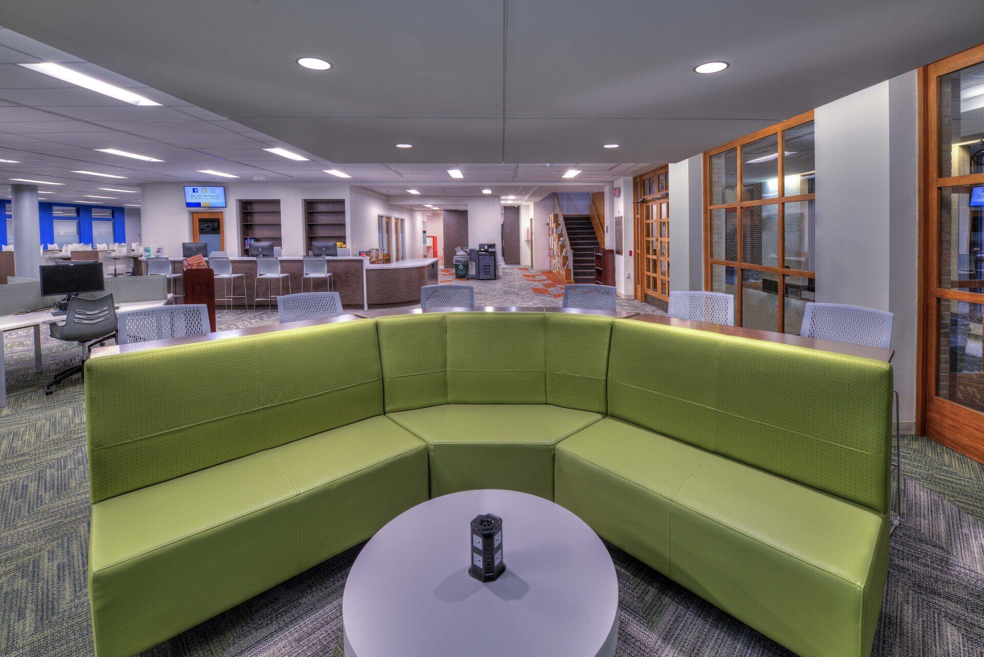 A living room with green couches and a round table.