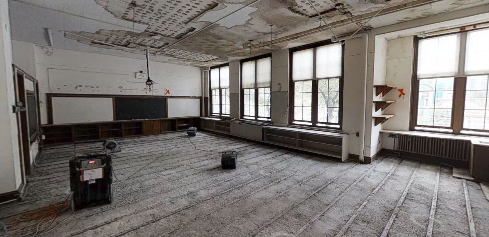 An empty classroom with a lot of windows and a blackboard.