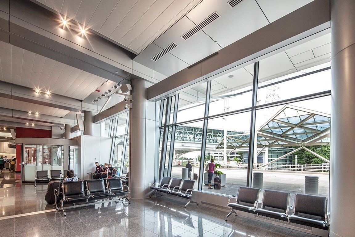 A waiting room at an airport with a lot of windows and chairs.