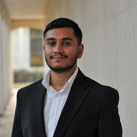 A man with a beard is wearing a suit and white shirt