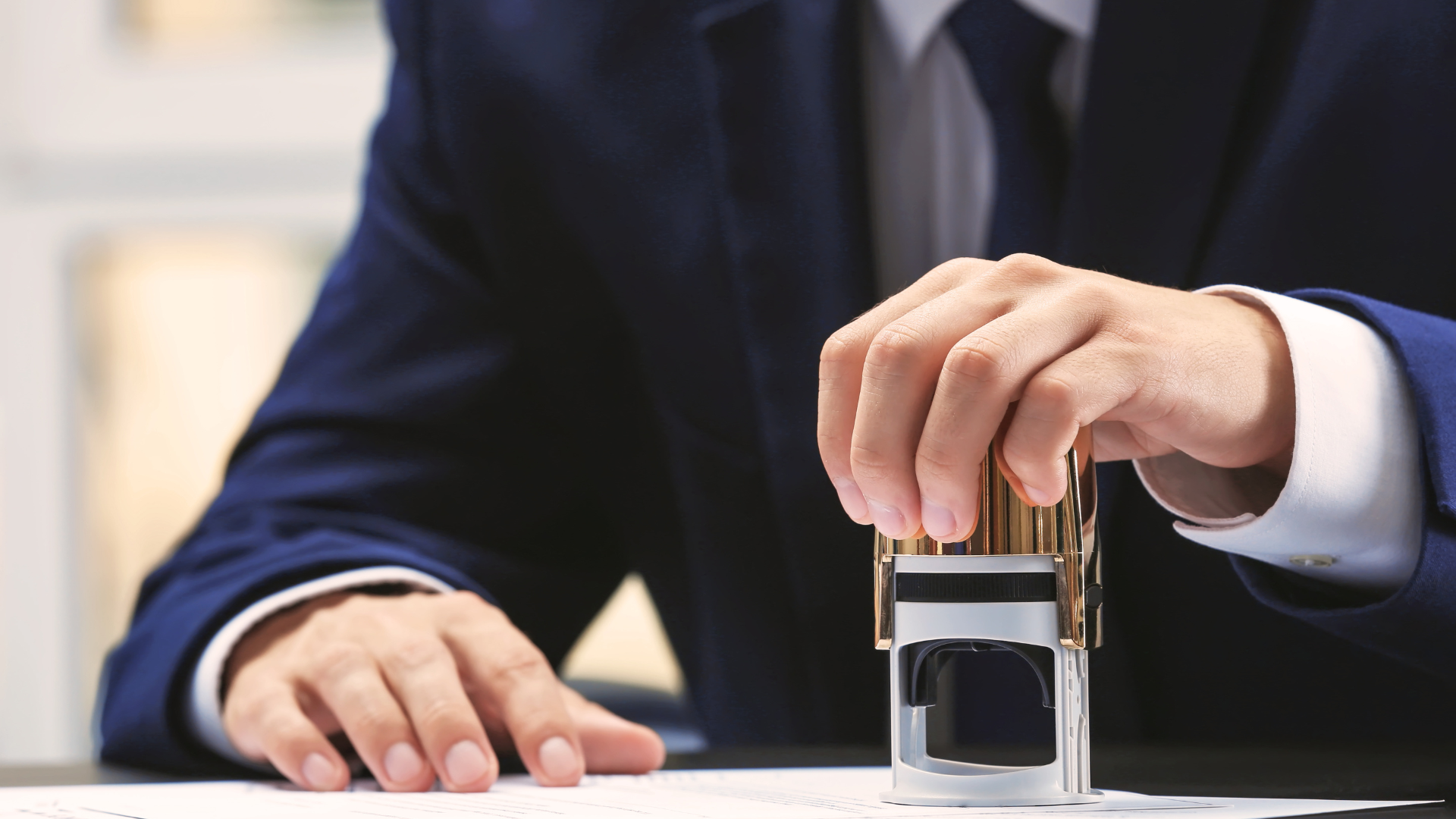 A man in a suit is stamping a document with a stamp.