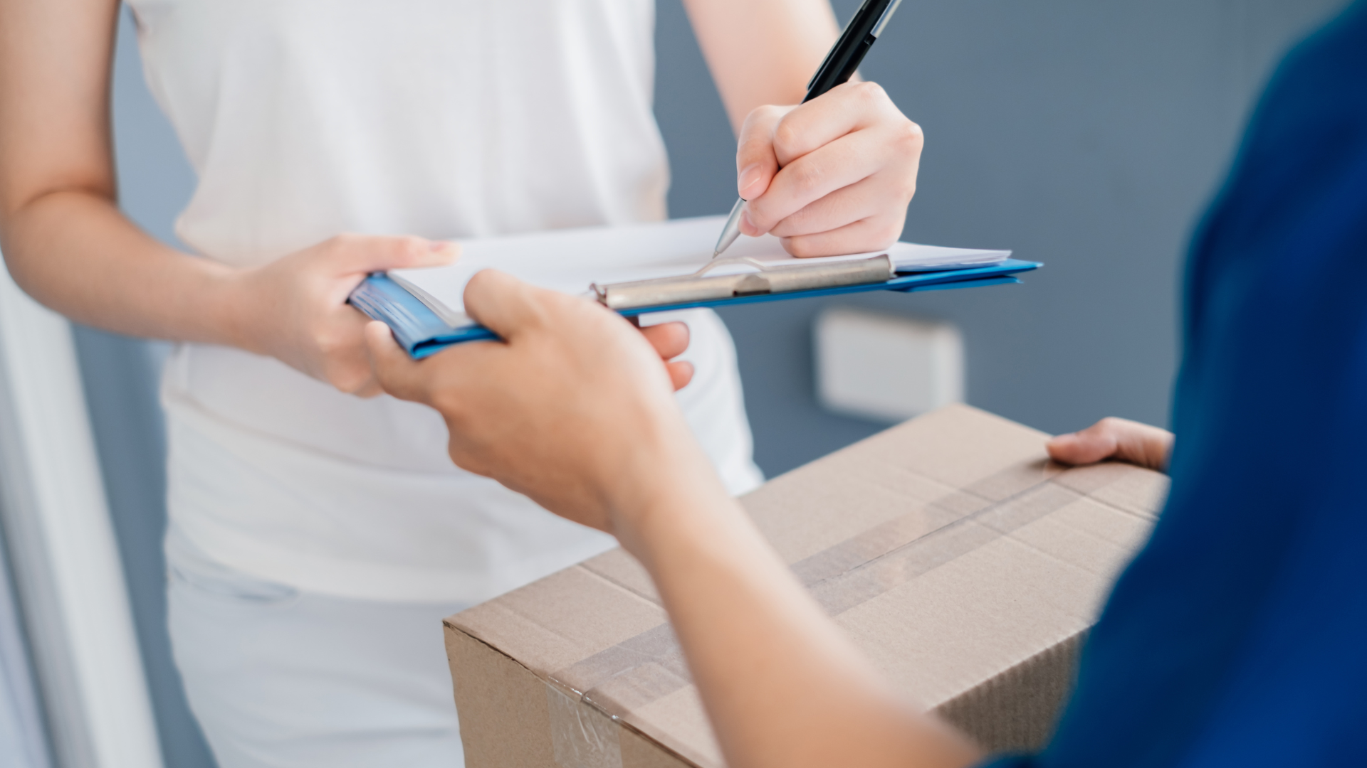 A woman is signing a delivery order on a clipboard.