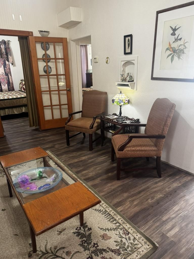 A cozy sitting area featuring two brown armchairs, a glass-topped coffee table, a small lamp, and wall art.