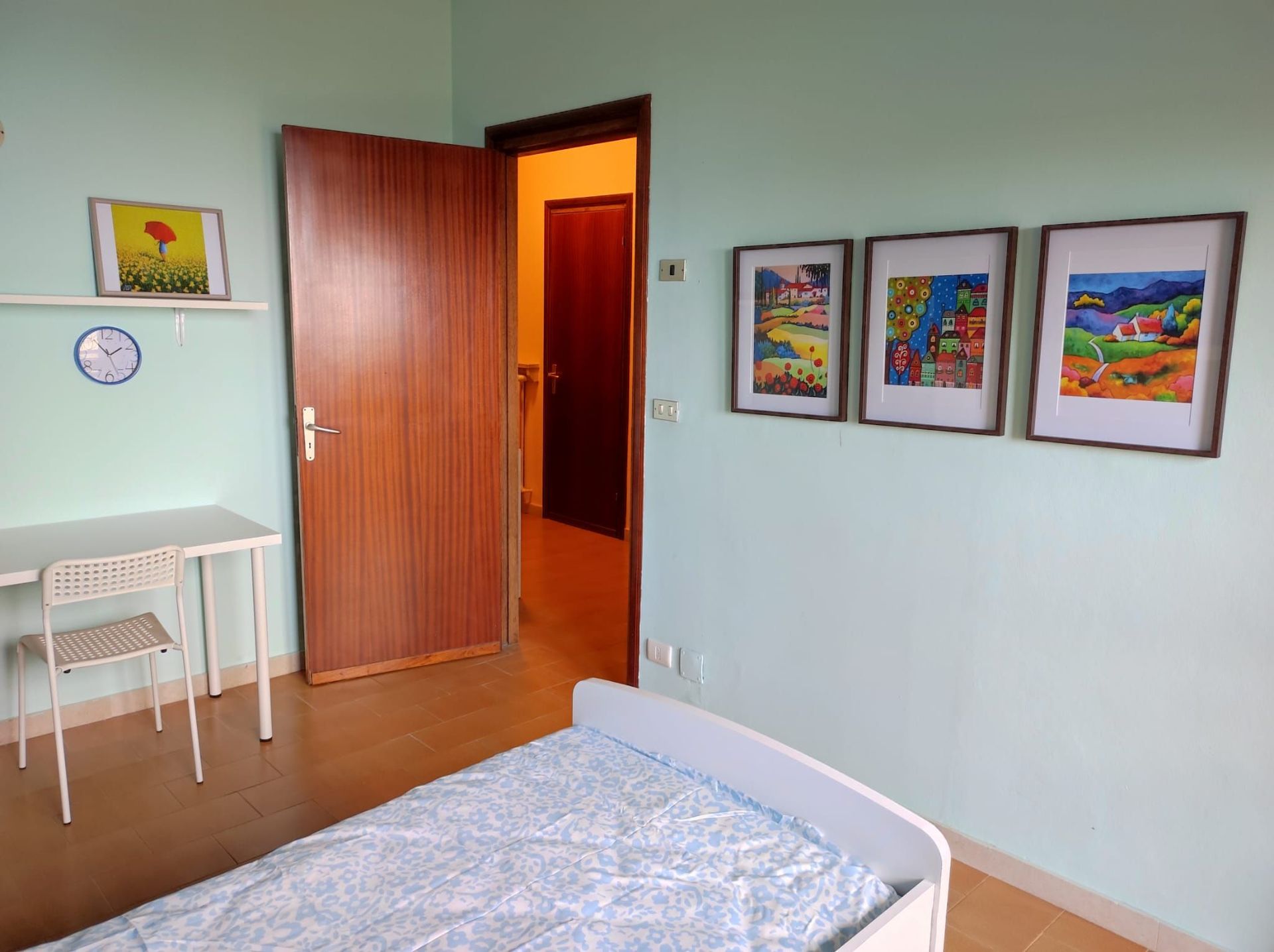 Una camera da letto con un letto, una scrivania e tre quadri sul muro