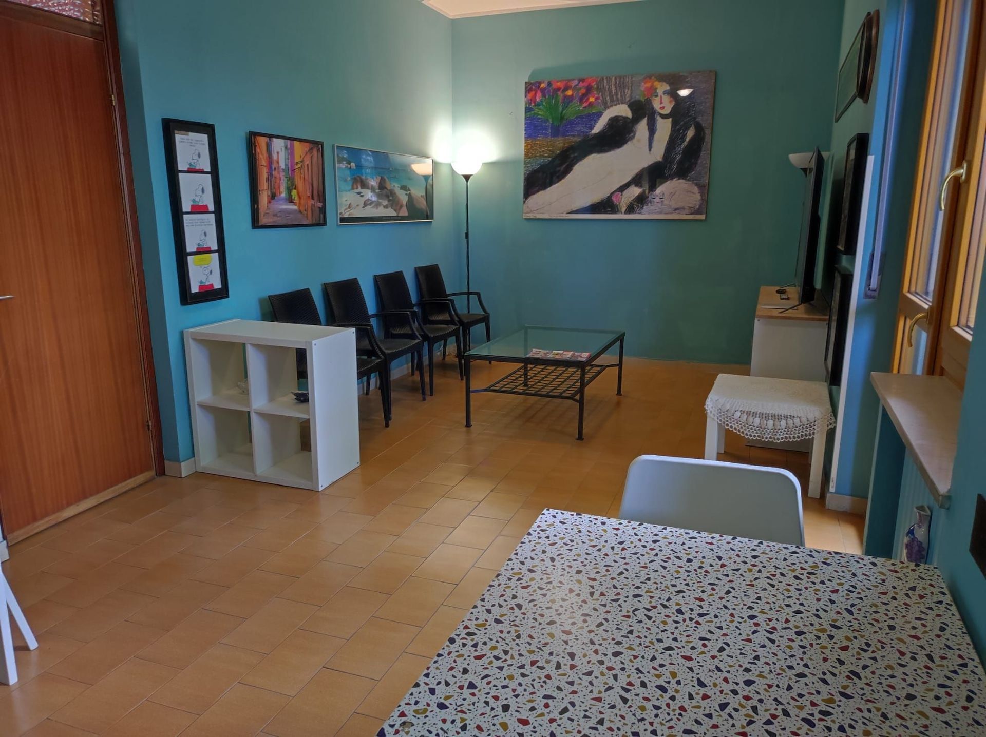 Un soggiorno con tavolo, sedie e un quadro alla parete.