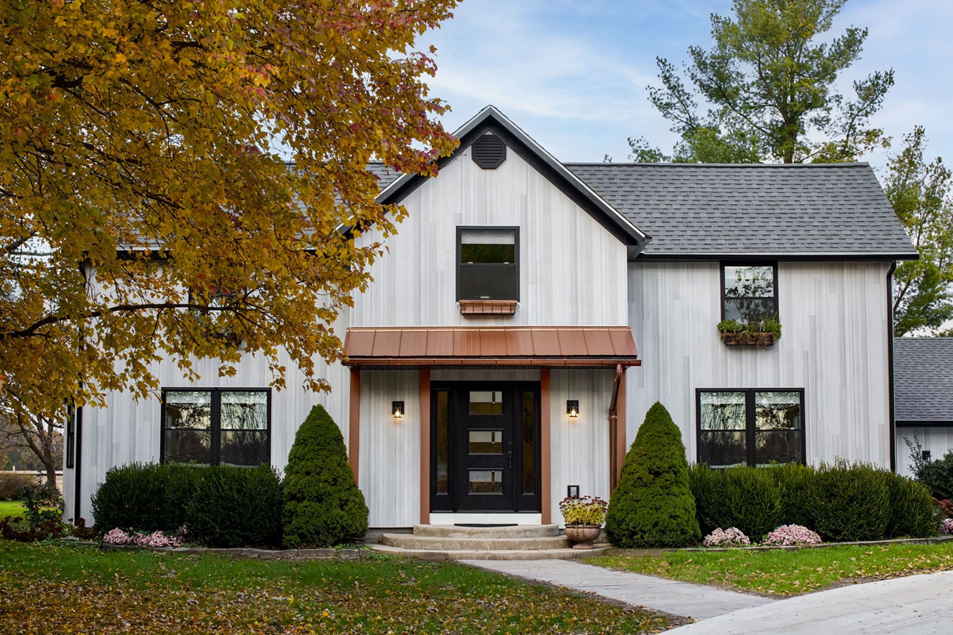 Modern farmhouse exterior with white siding, black trim, and copper accents.