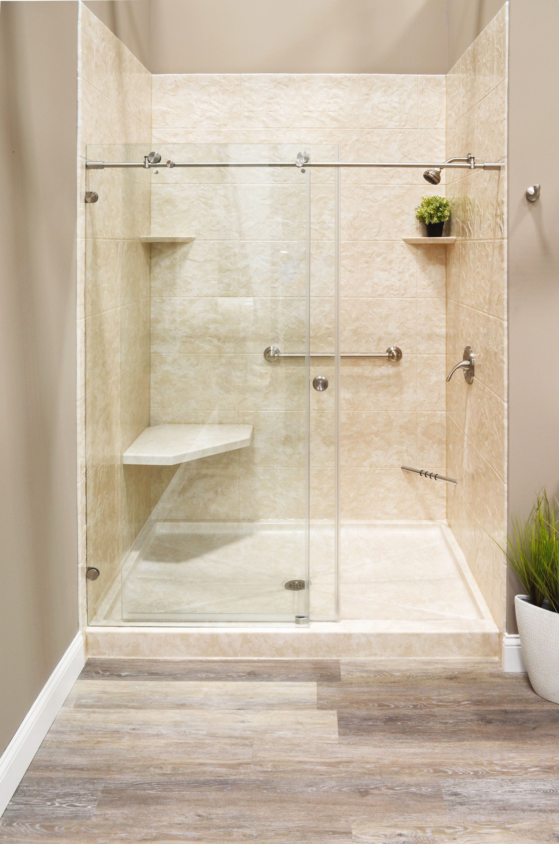 Accessible shower with glass doors, built-in bench, and grab bar. Light beige tile, wooden floor.