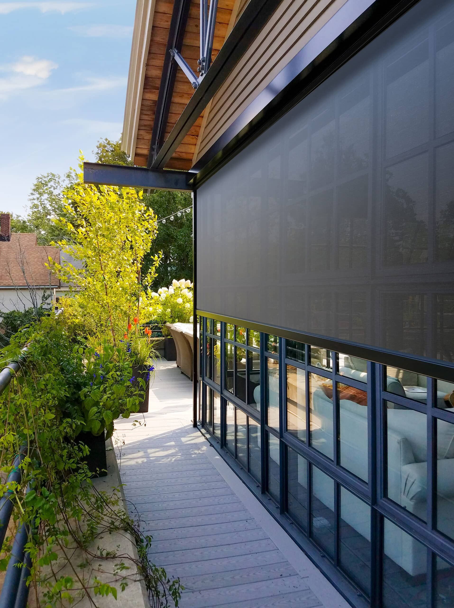 Balcony with a dark shade, overlooking lush greenery and a modern building.