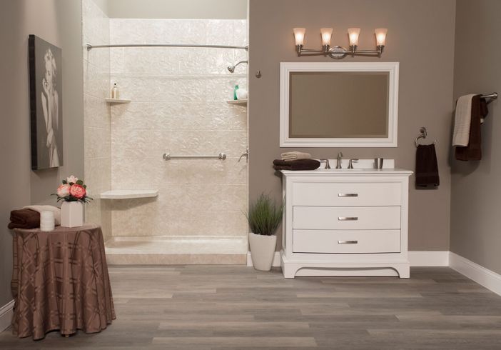 Bathroom with gray floors, shower, vanity, and accessible features like a grab bar.