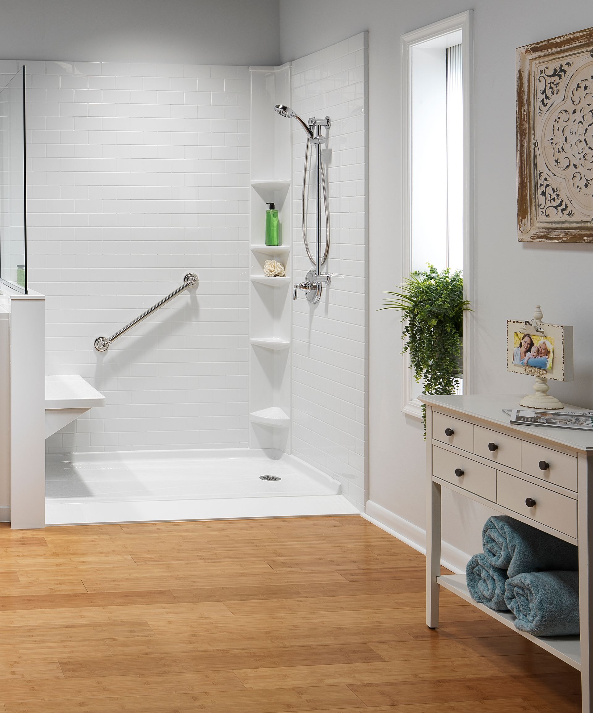 White accessible shower with grab bar, shelves, and a bench. Cork floor, bright room.