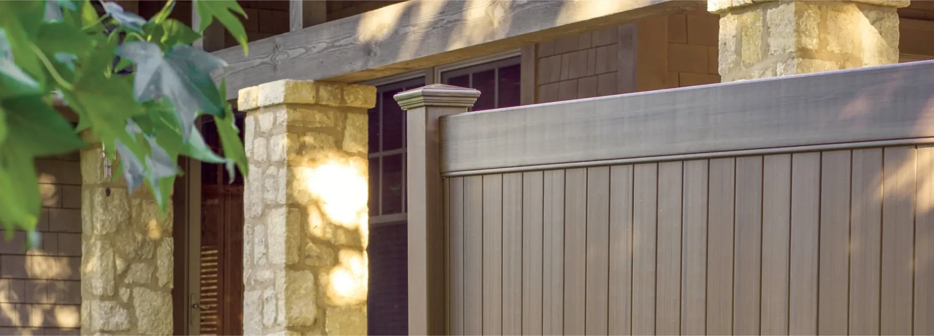 Stone pillars, wooden fence, and house facade in soft light.